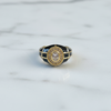 Gold ring with black and blue accents on a marble surface