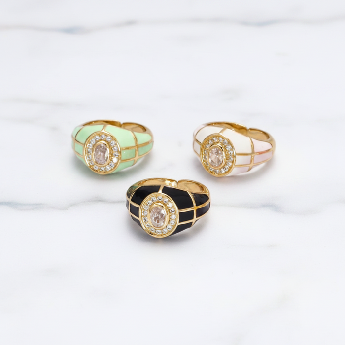 Three rings with different colored enameled settings on a light background