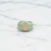Turquoise ring with gold accents and a central gemstone on a white fabric background