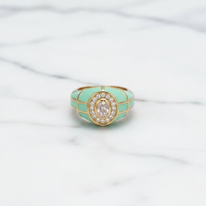 Turquoise ring with gold accents and a central gemstone on a white fabric background