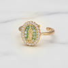 Gold ring with green gemstone and religious figure on a white background