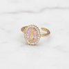 Gold ring with pink center and gemstones on a white background