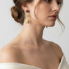 Close-up of a woman wearing gold earrings with a neutral background