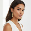 Woman wearing gold earrings with a plain background