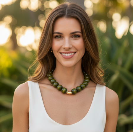 Woman wearing a white top and green necklace with a blurred natural background
