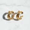 Gold hoop earrings on a light gray textured background