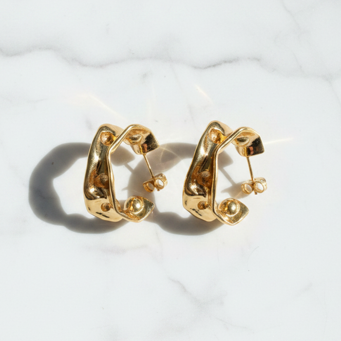 Gold hoop earrings on a light gray textured background