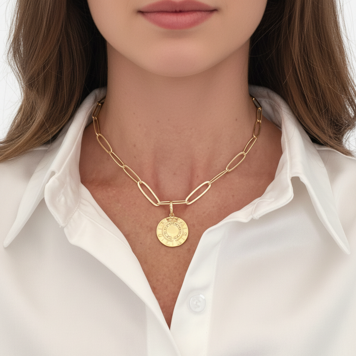 Gold chain necklace with a pendant worn by a person in a white shirt.