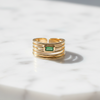 Gold ring with a green gemstone on a marble surface