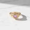 Gold ring with a heart-shaped pink gemstone on a light background