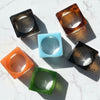 Set of colorful square bangles on a textured white surface
