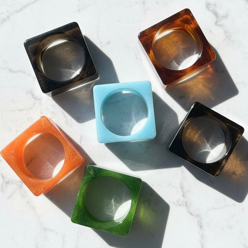 Set of colorful square bangles on a textured white surface