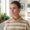 Woman wearing a striped sweater and wooden bead necklace indoors