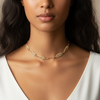 Woman wearing a gold necklace with a neutral background