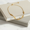 Gold necklace with leaf designs on a stack of books