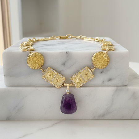 Gold bracelet with purple pendant on a marble surface