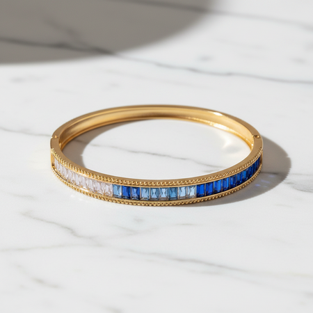 Gold bracelet with blue and white stones on a light fabric background