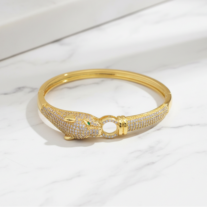 Gold bracelet with diamond accents on a white marble surface