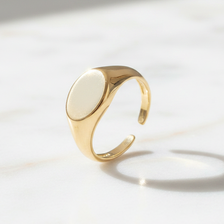 Gold ring with a white stone on a light background