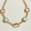 Gold necklace with square pastel stones on a white book
