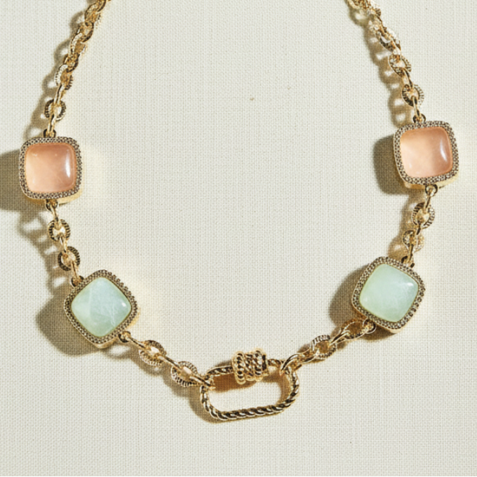 Gold necklace with square pastel stones on a white book