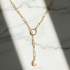 Gold necklace with a pendant on a marble surface