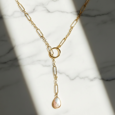 Gold necklace with a pendant on a marble surface