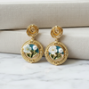 Gold earrings with floral design on a marble surface
