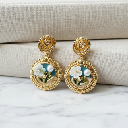 Gold earrings with floral design on a marble surface