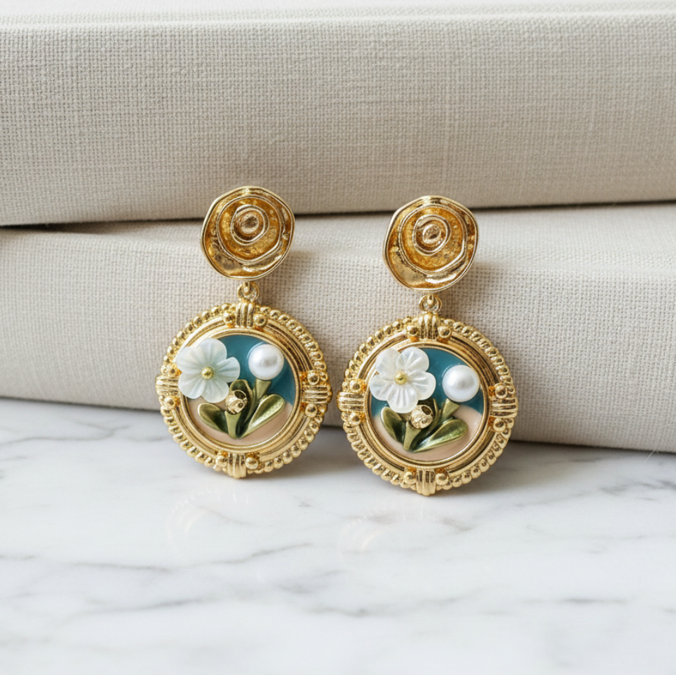 Gold earrings with floral design on a marble surface