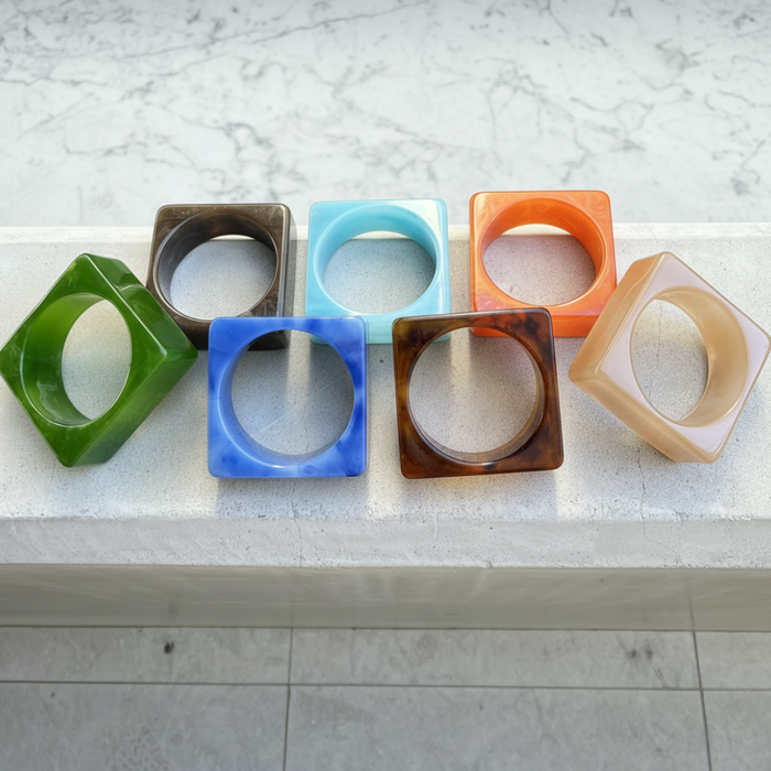 Set of colorful square-shaped bangles on a marble surface
