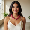 Woman wearing a pink necklace in a bright room with large windows.