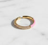 Gold hoop ring with pink accent on a light gray background