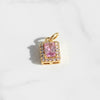 Gold pendant with a pink gemstone on a white background