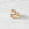 Gold ring with colorful gemstones on a light gray background
