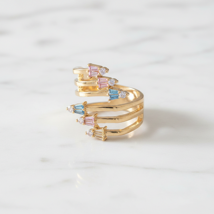 Gold ring with colorful gemstones on a light gray background