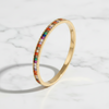 Gold ring with colorful gemstones on a light background