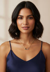 Woman wearing a gold necklace and navy blue top against a beige background