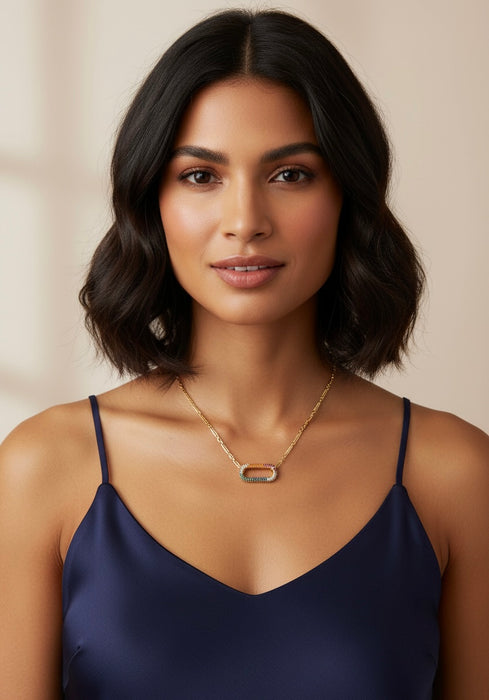 Woman wearing a gold necklace and navy blue top against a beige background