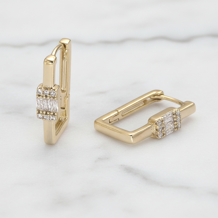 Gold hoop earrings with diamond accents on a light marble background
