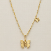 Gold butterfly necklace on a beige background