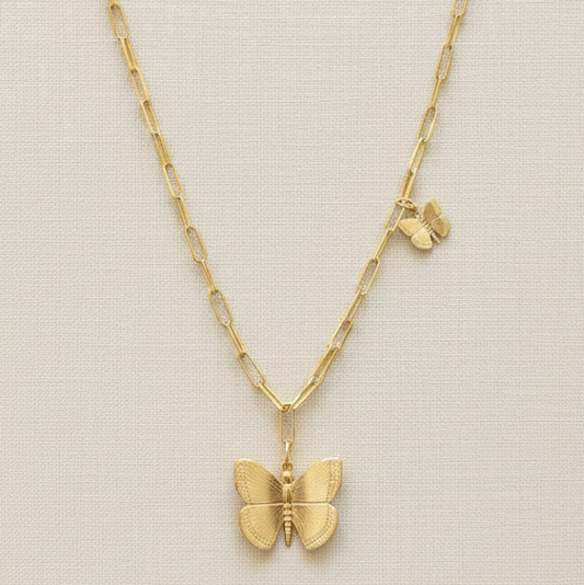 Gold butterfly necklace on a beige background