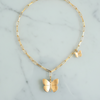 Gold butterfly necklace on a marble surface