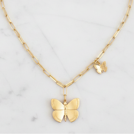Gold butterfly pendant necklace on a marble background
