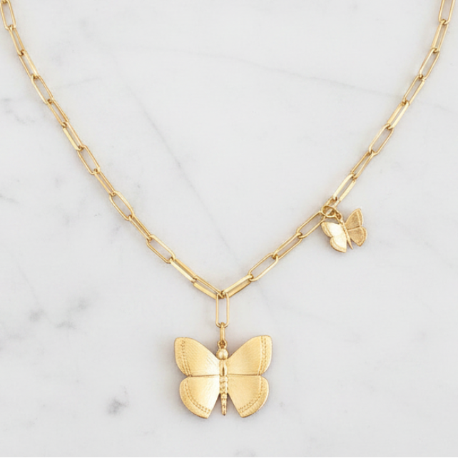 Gold butterfly pendant necklace on a marble background