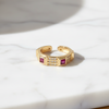 Gold ring with embedded red stones on a marble surface