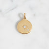 Gold pendant with star and moon design on a light gray background