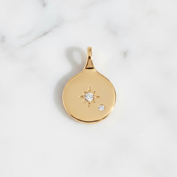 Gold pendant with star and moon design on a light gray background