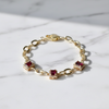 Gold bracelet with red gemstones on a marble surface