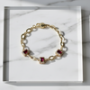Gold bracelet with red gemstones on a marble surface